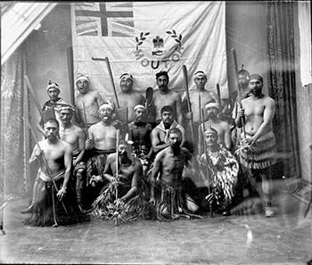 Maori men standing in front of the Moutoa flag