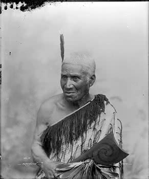 Maori man wearing korowai and carrying a tewhatewha