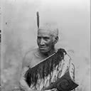 Maori man wearing korowai and carrying a tewhatewha